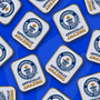 multiple Officially Amazing pin badges scattered across blue background